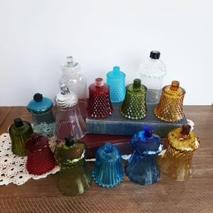 Puede incluir: Una colección de coloridos candelabros de vidrio en varias formas y texturas. Los candelabros son en tonos de rojo, verde, azul y ámbar, con opciones de vidrio transparente y texturizado. Algunos tienen un patrón de diamantes, otros son lisos.
