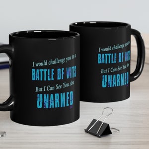 May include: Two black coffee mugs with a white design. The text on the mugs reads "I would challenge you to a BATTLE OF WITS But I Can See You Are UNARMED".