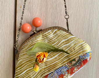 Oranje Kiss-lock-etui met Kanzashi-bloemdecoratie.