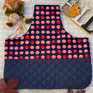 May include: A blue quilted project bag with a pink and red tomato print. The bag has a zipper closure and a handle.
