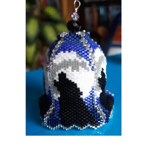 May include: A bell-shaped ornament crafted from small glass beads in a pattern of blue, white, and black. The top features a single black bead and a silver-toned metal loop for hanging. The beadwork is intricate, creating a smooth, rounded structure.
