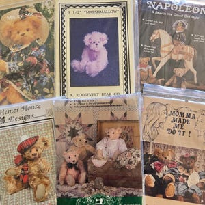 May include: Six sewing pattern packets for teddy bears, including Marcy Sue, 9 1/2 inch Marshmallow, Napoleon, Hemer House Designs, and Momma Made Me Do It. Each plastic-wrapped package features illustrations of finished bears in various outfits.