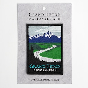 May include: A black and white embroidered patch with a scenic view of a river winding through a valley with mountains in the background. The text "Grand Teton National Park" is embroidered in white on a black background. The text "Official Park Patch" is printed in black on a gray background.