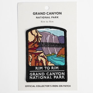 May include: An iron-on patch featuring a colorful illustration of the Grand Canyon National Park with the text "Rim to Rim" and "Grand Canyon National Park". The patch is on a white card with the text "Official Collector's Iron-On Patch".