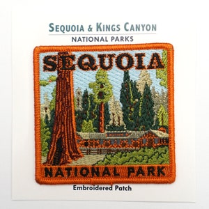 May include: Embroidered patch with an orange border and the text "Sequoia National Park". The patch features a depiction of a giant sequoia tree, a log cabin, and other trees in a forest setting.