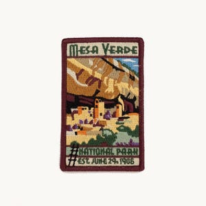 May include: A rectangular embroidered patch featuring a landscape of Mesa Verde National Park. The design includes cliff dwellings, rock formations, and the text "Mesa Verde National Park Est. June 29, 1906" with a dark maroon border.