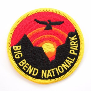 May include: A yellow, red, and black embroidered patch with the text "Big Bend National Park" and a stylized image of a mountain range with a red sunset and a bird flying overhead.
