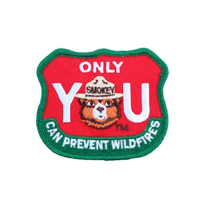 Peut inclure: Un écusson brodé vert et rouge avec les mots "Only You Can Prevent Wildfires" et un dessin animé de Smokey Bear portant un chapeau de ranger.