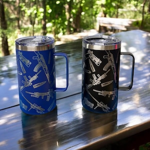 May include: Two stainless steel travel mugs with a black and blue finish. Both mugs feature a repeating pattern of guns and bullets. The mug on the left is blue and the mug on the right is black.