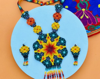 May include: A colorful beaded necklace and earrings set with a starburst design in shades of yellow, orange, red, blue, and green. The necklace has a fringe of beads.