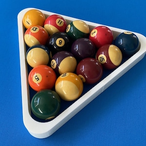 Könnte beinhalten: Ein weißer dreieckiger Ständer hält 15 Billardkugeln, darunter eine durchgehend gelbe Kugel mit der Nummer 1, eine durchgehend rote Kugel mit der Nummer 3, eine durchgehend grüne Kugel mit der Nummer 8, eine durchgehend blaue Kugel mit der Nummer 12 und eine durchgehend braune Kugel mit der Nummer 15.