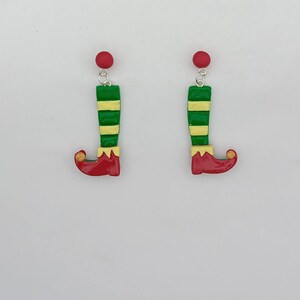 May include: A pair of elf shoe earrings with green and yellow striped stockings, red shoes, and gold accents.