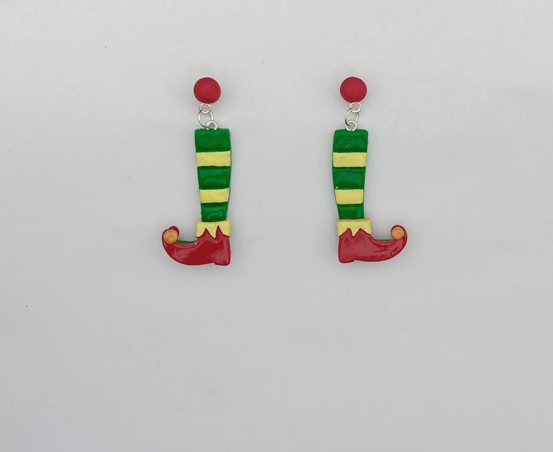 May include: A pair of elf shoe earrings with green and yellow striped stockings, red shoes, and gold accents.