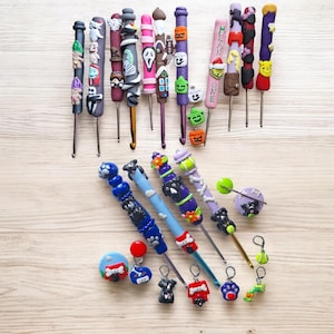 Op de afbeelding: Een verzameling van 18 kleurrijke haaknaalden met verschillende Halloween- en hondenthema's. De haaknaalden zijn gemaakt van metaal en hebben verschillende maten. De versieringen zijn gemaakt van polymer clay en zijn met de hand beschilderd.