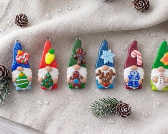 Pode incluir: Seis ornamentos em miniatura de gnomos com temas festivos. Cada gnomo usa um chapéu alto em azul, vermelho, verde ou bordô, decorado com ícones como um floco de neve, bengala doce, boneco de gengibre ou árvore de Natal, e segura um item.