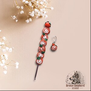 May include: A pair of orange and white swirl earrings with a pumpkin charm. The earrings are attached to a crochet hook with a string of orange and white swirl beads.