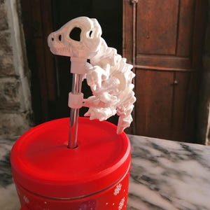 Op de afbeelding: Witte plastic dinosaurus skelet strooisel topper voor een rood-witte feestthema beker.