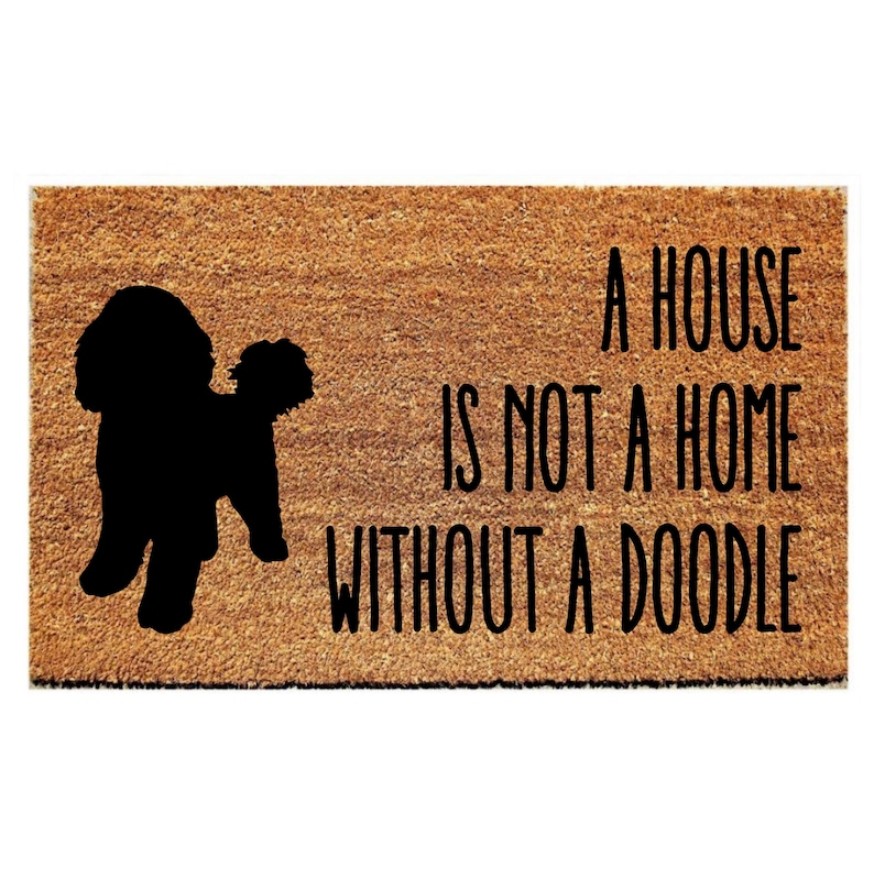 Puede incluir: Una alfombra de bienvenida marr&oacute;n con una silueta negra de un perro doodle y el texto "Una casa no es un hogar sin un doodle."