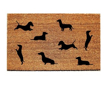 May include: A brown coir doormat with a silhouette of eight dachshunds in various poses.