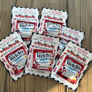 Pu&ograve; includere: Un set di otto biglietti di San Valentino a tema bacche. Ogni biglietto presenta una piccola confezione di snack di frutta Welch's e il testo "Sono BERRY felice che siamo amici!" con un design a forma di cuore. I biglietti sono decorati con strisce bianche e nere e cuori.