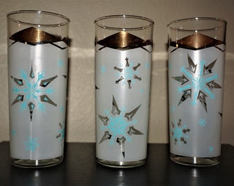 May include: Three frosted glass tumblers with a gold rim and a snowflake design in blue and white.
