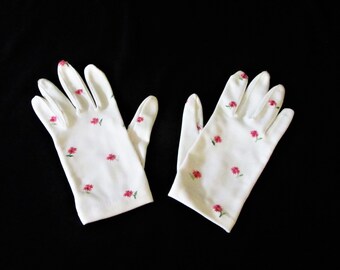 Puede incluir: Un par de guantes de algodón blanco con un delicado estampado floral en rosa. Los guantes están hechos de una tela suave y ligera y tienen un diseño clásico.