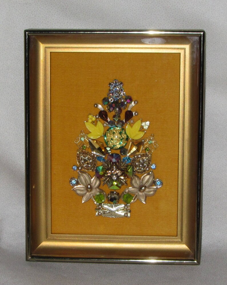 May include: A framed artwork featuring a yellow, green, and blue jeweled tree design on a mustard yellow background.