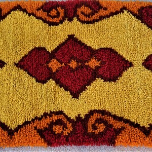 May include: A vintage rug with a geometric pattern in shades of orange, yellow, and red. The rug has a fluffy texture and a unique design.