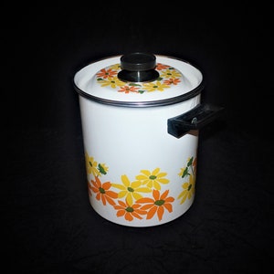 May include: White enamelware pot with a black lid and handle. The pot has a floral design with yellow and orange flowers.