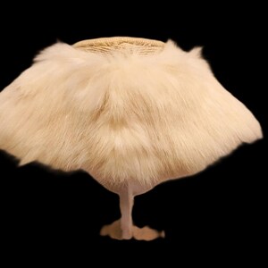 May include: A vintage-style hat with a cream-colored fur brim and a woven top. The hat is displayed on a stand against a black background, showcasing its unique design and texture. This accessory is perfect for costume parties or vintage fashion.