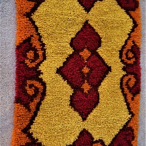 May include: A colorful, geometric rug with a yellow, orange, and red pattern. The rug is made of a soft, fluffy material and has a vintage look.