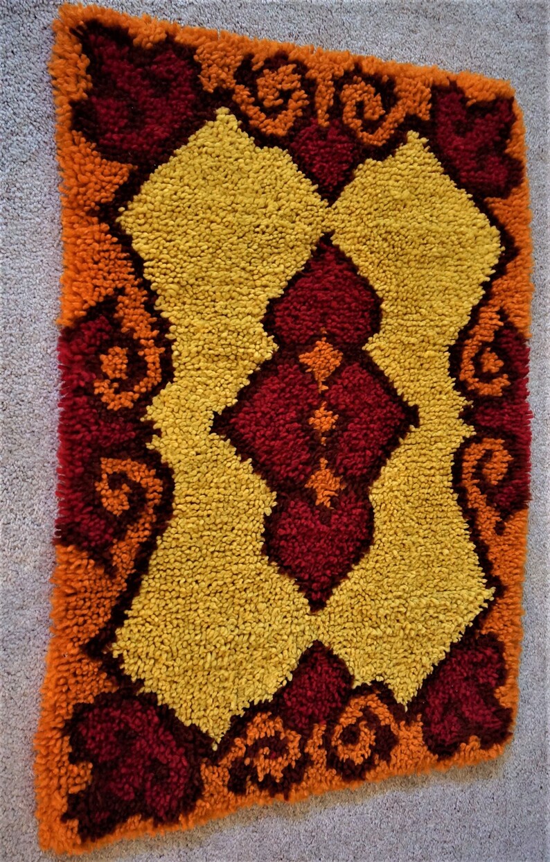 May include: A colorful, geometric rug with a yellow, orange, and red pattern. The rug is made of a soft, fluffy material and has a vintage look.
