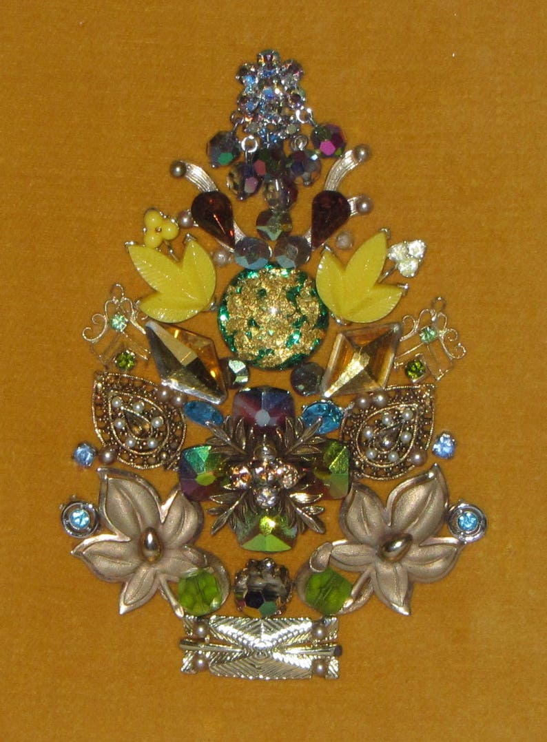 May include: A gold, green, and yellow jeweled Christmas tree ornament with a variety of rhinestones and beads.