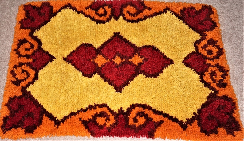 May include: A vintage shag rug with a geometric design in shades of orange, yellow, and red.