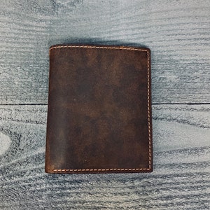 May include: A brown leather wallet with a stitched edge.