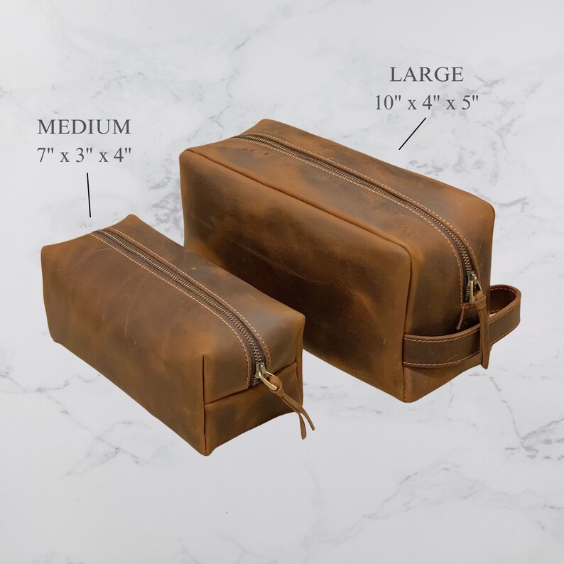 May include: Two brown leather travel toiletry bags with zippers. The smaller bag measures 7 inches by 3 inches by 4 inches. The larger bag measures 10 inches by 4 inches by 5 inches.