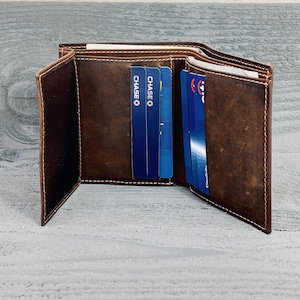 May include: A brown leather trifold wallet with multiple card slots. The wallet is open and shows several cards, including two Chase credit cards.