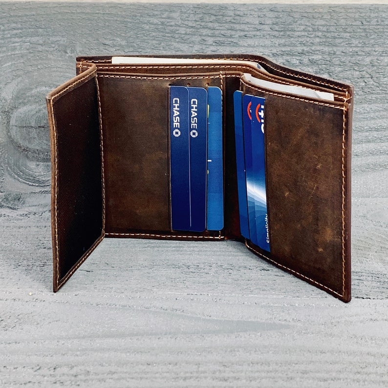 May include: A brown leather trifold wallet with multiple card slots. The wallet is open and shows several cards, including two Chase credit cards.