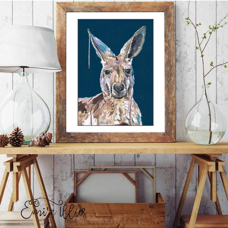 May include: A framed painting of a kangaroo with a blue background. The kangaroo is painted in a realistic style with brown, tan, and white fur. The painting is framed in a rustic wooden frame.