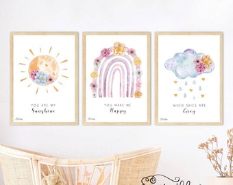 May include: Three watercolor prints with floral designs and inspirational quotes. The first print features a sun with the quote "You are my sunshine". The second print features a rainbow with the quote "You make me happy". The third print features a cloud with raindrops and the quote "When skies are grey".