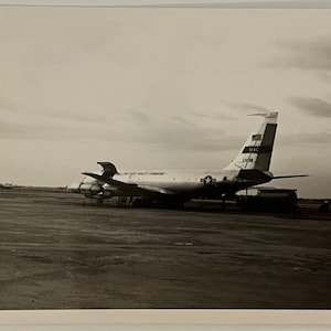 May include: A black and white photo of a large, silver airplane on a tarmac. The airplane has the words "Military Airlift Command" on the side and "MAC" on the tail.