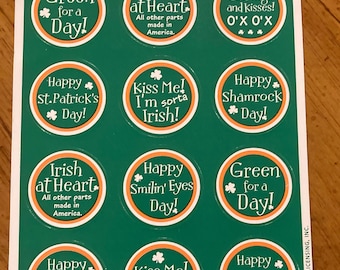 Puede incluir: Una hoja de nueve pegatinas redondas con lemas de temática irlandesa y diseños de tréboles. Las pegatinas están sobre un fondo verde con bordes naranjas. Los lemas incluyen "Green for a Day!" "Irish at Heart" "Kiss Me! I'm sorta Irish!" "Happy St. Patrick's Day!" "Happy Shamrock Day!" y "Irish Hugs and Kisses! O'X O'X".