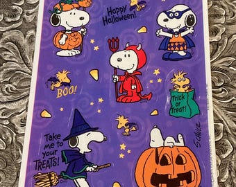 May include: A sheet of Halloween stickers featuring Snoopy and Woodstock characters in costumes. The stickers include phrases like "Happy Halloween!" and "Trick or Treat!" on a purple background.