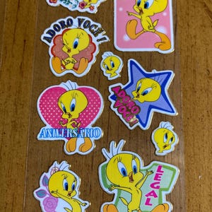 Puede incluir: Una hoja de pegatinas con un personaje de pájaro amarillo con diferentes frases en portugués. Las frases incluyen "Feriado", "Adoro Você", "Importante", "Aniversario" y "Legal".