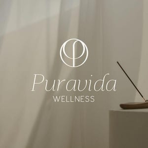 Può includere: Un logo bianco con il testo "Puravida WELLNESS" e un design circolare stilizzato. Un porta incenso in legno con un bastoncino di incenso acceso è su una superficie bianca.