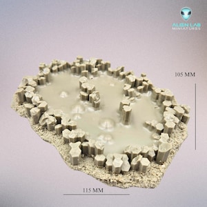 Może przedstawiać: Rektangularny, teksturowany element terenu z żywicy w kolorze beżowym z podniesionym, okrągłym elementem wodnym. Element ma wymiary 115 mm x 105 mm. Alien Lab Miniatures.