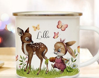 May include: White enamel mug with a gold rim featuring a deer and a bunny with a carrot. The mug has a green, brown, and pink floral design with butterflies and the name "Lilli" written in black.