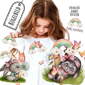 Könnte beinhalten: Bügelbild mit zwei Hasen, einem Regenbogen, Schmetterlingen und Wolken. Der Text "hello sunshine" ist im Design enthalten. Das Design ist für helle und dunkle Stoffe geeignet.