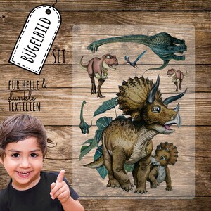 Könnte beinhalten: Ein Set Bügelbilder mit Dinosauriern für helle und dunkle Stoffe. Das Set enthält einen Tyrannosaurus Rex, einen Triceratops, ein Baby Triceratops, einen Pterodactylus und zwei Brachiosaurus. Die Bügelbilder sind auf einer transparenten Folie gedruckt.