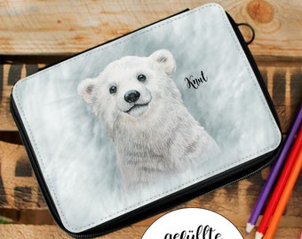 Könnte beinhalten: Eine schwarze Reißverschluss-Federmappe mit einer weißen Eisbären-Illustration und dem Namen "Knut" darauf gedruckt. Die Federmappe liegt auf einer Holzoberfläche mit Buntstiften.